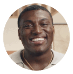 Smiling man in a light-colored shirt with a gold chain, set against a circular coral background. Represents positivity, confidence, and the supportive Noom community.
